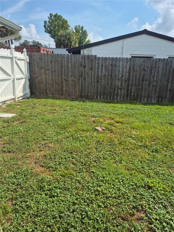 A grassy backyard features a wooden privacy fence and a white vinyl gate — 2604 REEF COURT, ORLANDO, FL