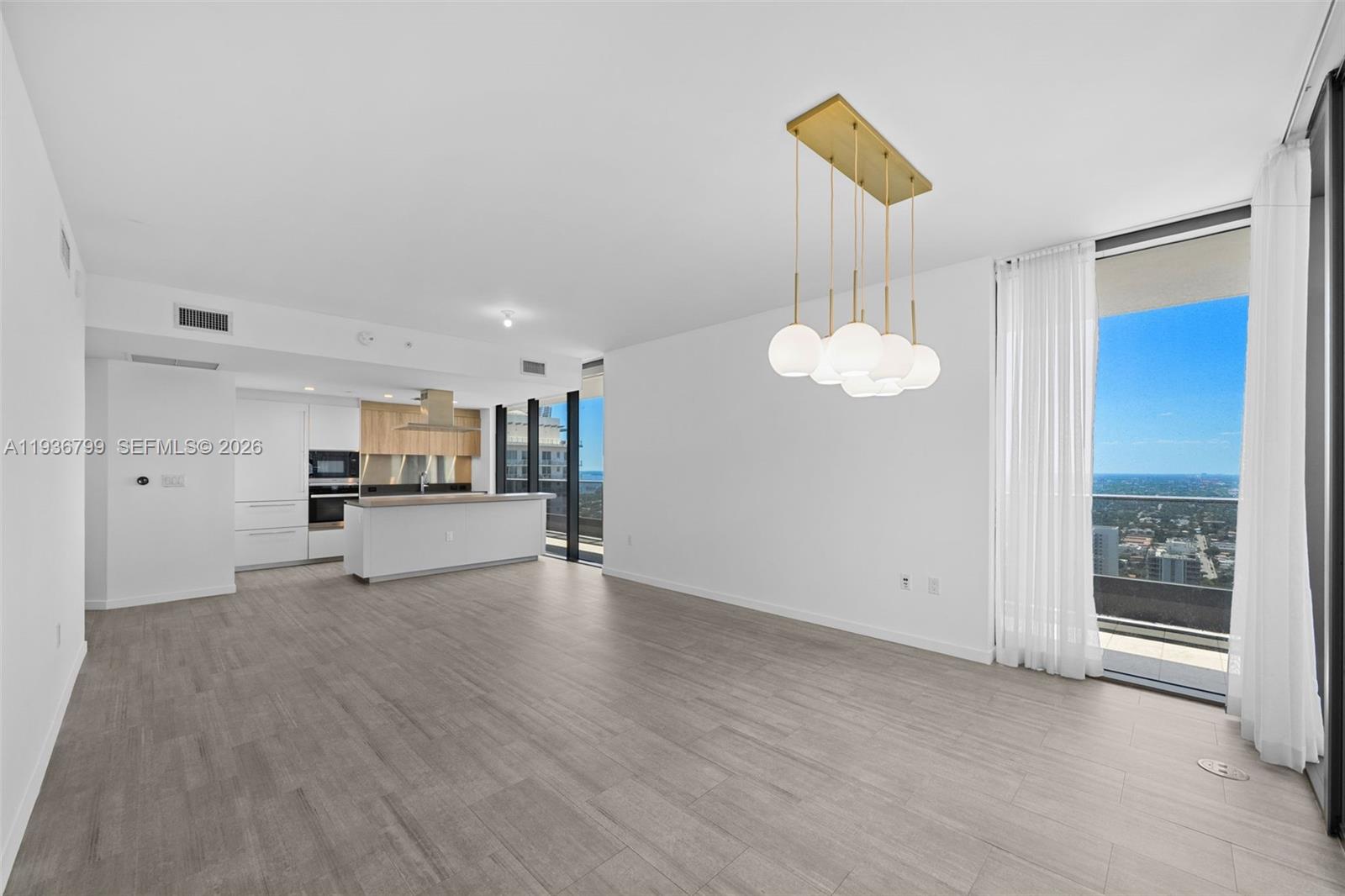 An open-concept living area features light wood-look flooring, a modern kitchen, and a balcony view — 1000 Brickell Plz # 4212, Miami FL 33131, MIAMI, FL