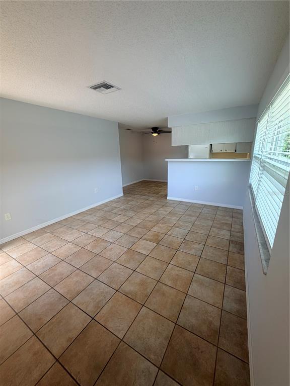 An open-concept living area features light-colored walls, tile flooring, and a kitchen breakfast bar — 6050 CHESHAM DRIVE UNIT 5, NEW PORT RICHEY, FL