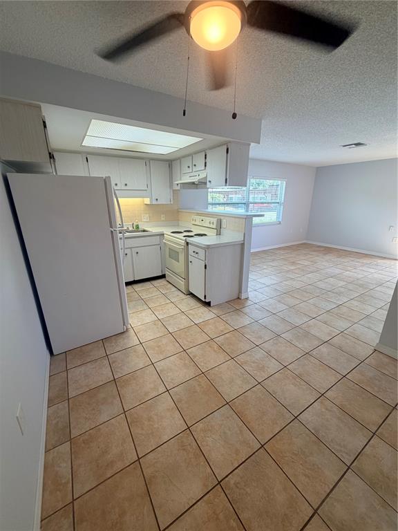 A kitchen with white cabinets and tile flooring opens into a living area — 6050 CHESHAM DRIVE UNIT 5, NEW PORT RICHEY, FL