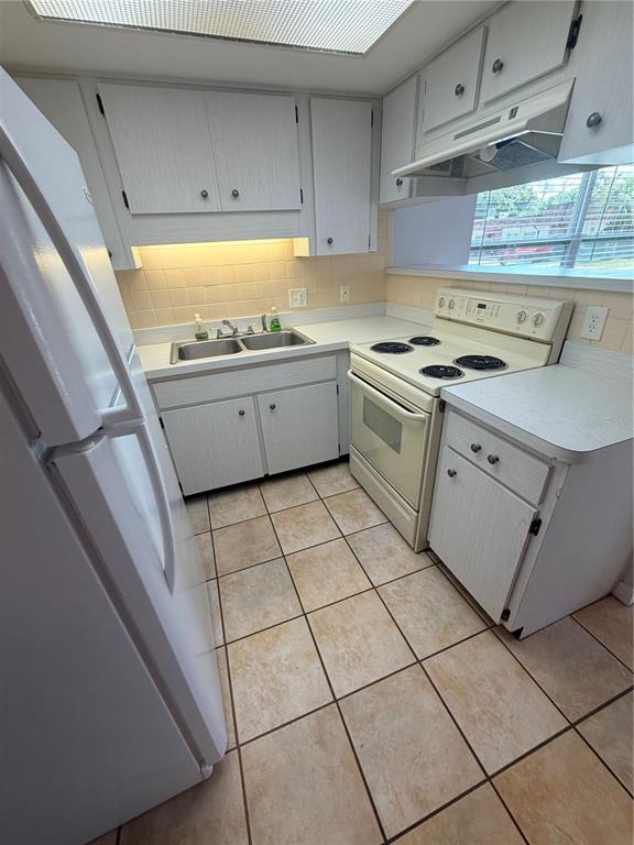 A kitchen features white cabinets, a white refrigerator, a stove, and tiled floors — 6050 CHESHAM DRIVE UNIT 5, NEW PORT RICHEY, FL