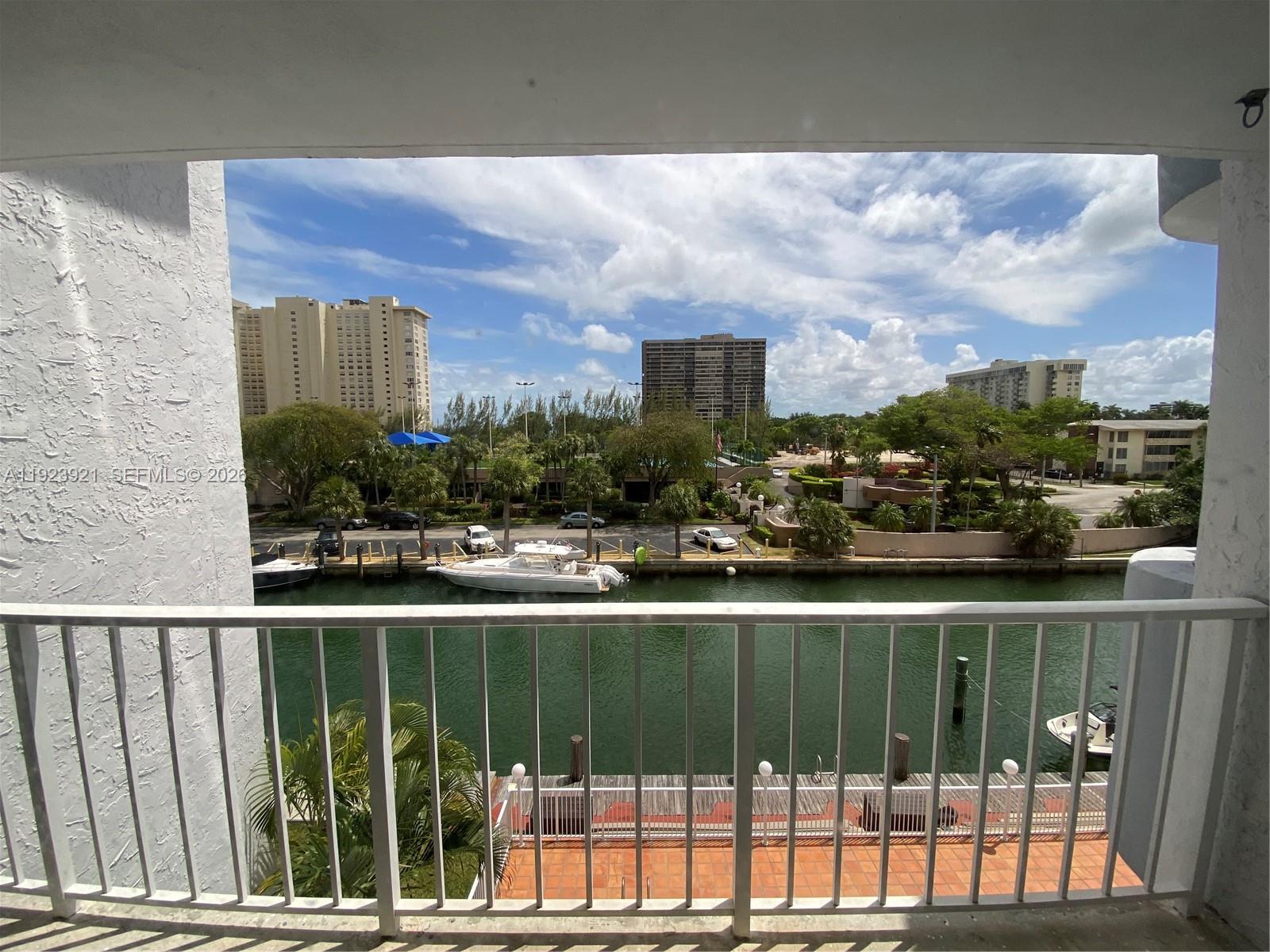 A balcony view overlooks a canal with docked boats and surrounding residential buildings — 1650 NE 115th St # 405, Miami FL 33181, MIAMI, FL
