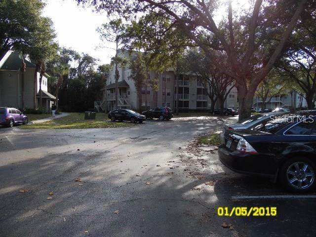 A parking lot sits in front of apartment buildings surrounded by large trees — 5962 WESTGATE DRIVE UNIT 204, ORLANDO, FL