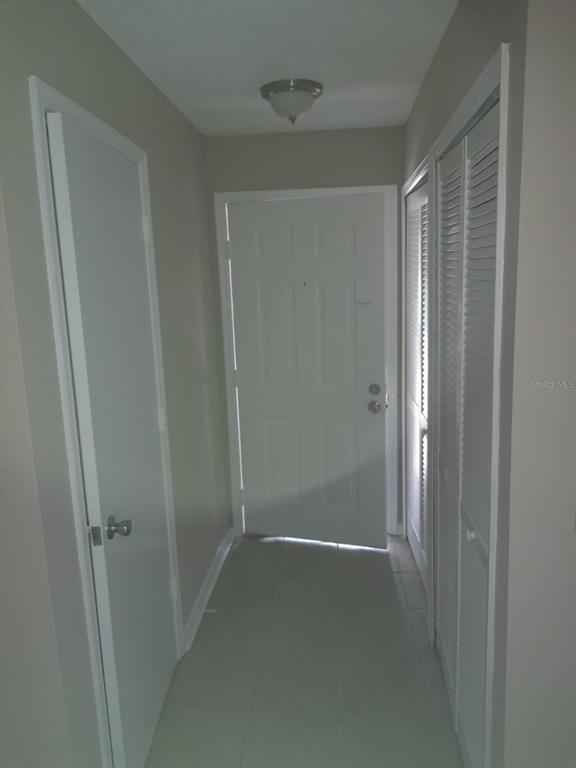 A narrow entryway features a white front door, tiled flooring, and two sets of closet doors — 5962 WESTGATE DRIVE UNIT 204, ORLANDO, FL