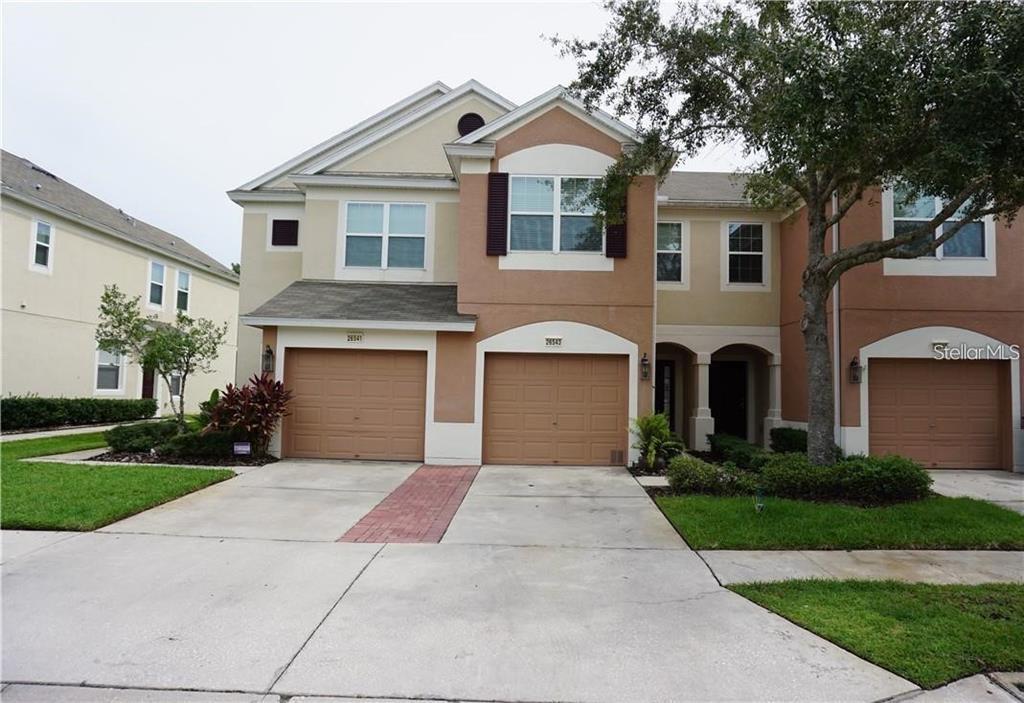 A two-story townhouse with two garage doors and a concrete driveway — 26543 CASTLEVIEW WAY, WESLEY CHAPEL, FL