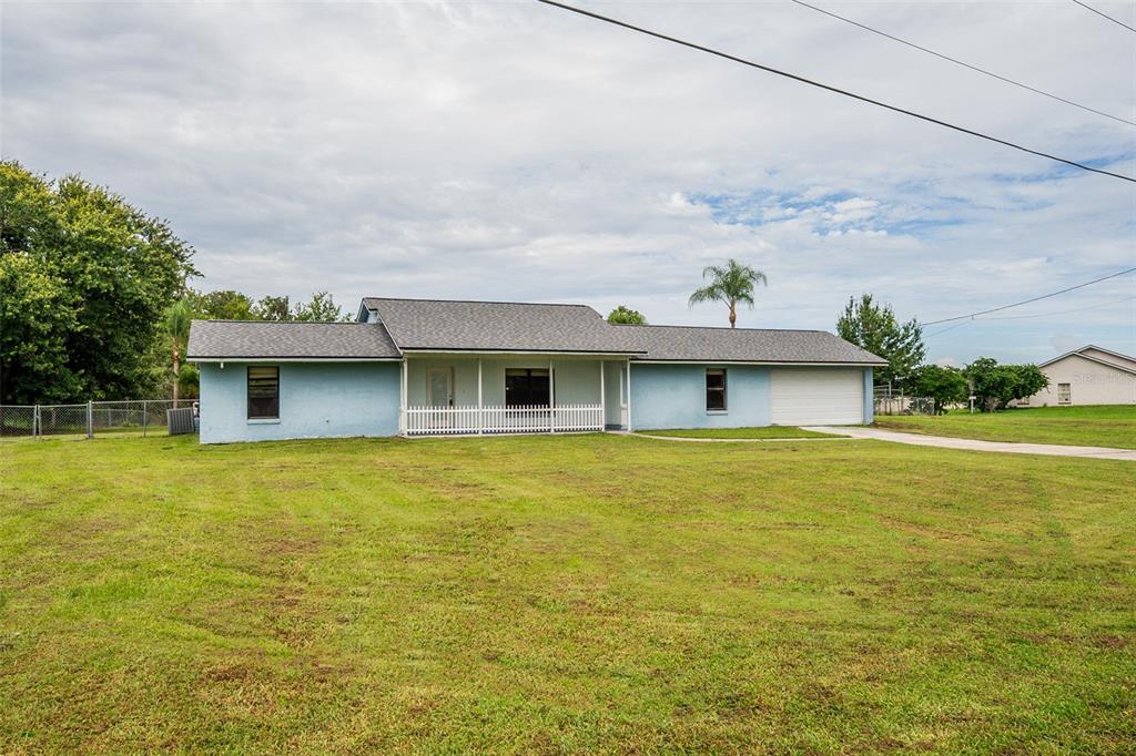 A single-story light blue house with a white porch railing and a two-car garage — 4148 BIG VALLEY BOULEVARD, KISSIMMEE, FL