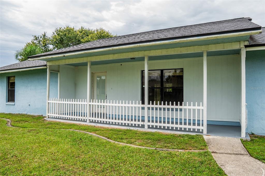 A light blue house features a covered front porch with a white picket railing — 4148 BIG VALLEY BOULEVARD, KISSIMMEE, FL