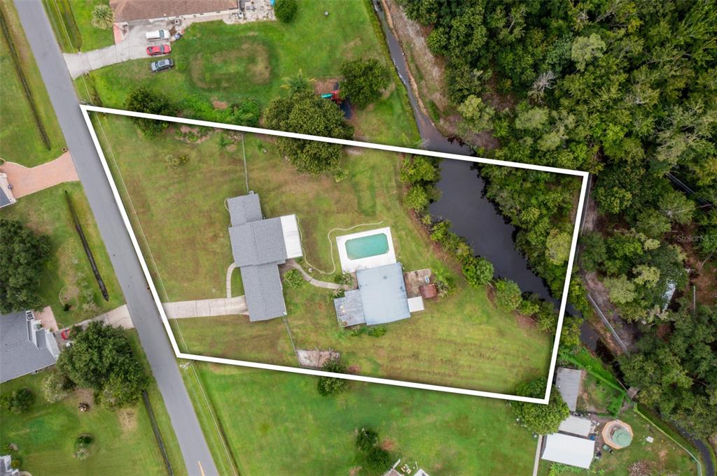 An aerial view shows a house with a pool on a large, grassy lot — 4148 BIG VALLEY BOULEVARD, KISSIMMEE, FL