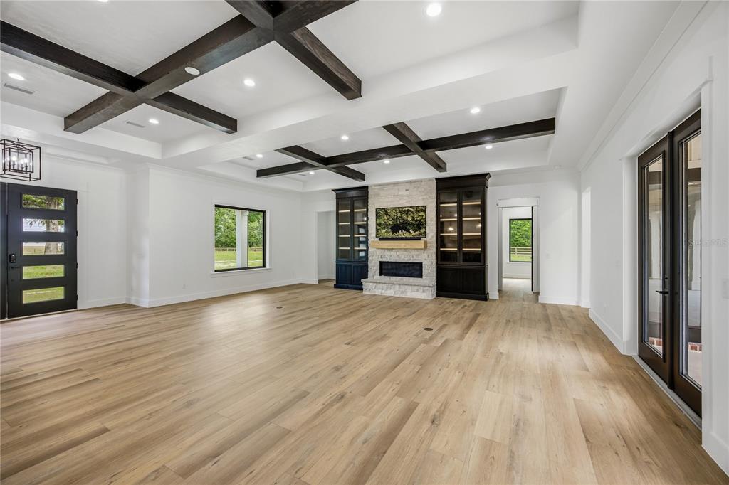 A spacious living room features a coffered ceiling with dark beams, stone fireplace, and wood flooring — 1224 NW 143RD STREET, NEWBERRY, FL