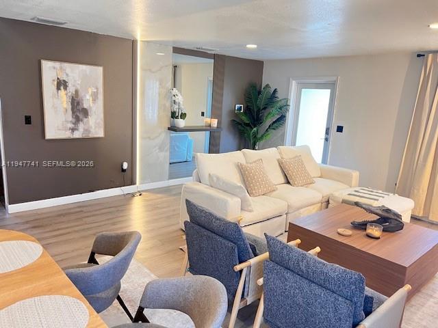 A living room features a white sectional sofa, two blue chairs, and a wooden coffee table — 601 NW 10th St, Hallandale Beach FL 33009, HALLANDALE BEACH, FL