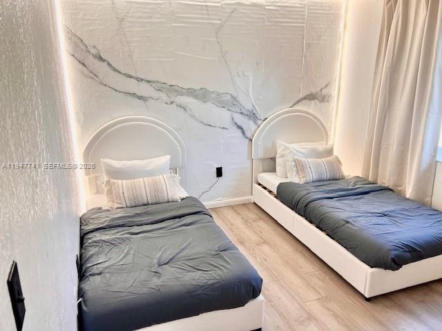 A bedroom features two twin beds against a white marble-patterned accent wall with backlighting — 601 NW 10th St, Hallandale Beach FL 33009, HALLANDALE BEACH, FL