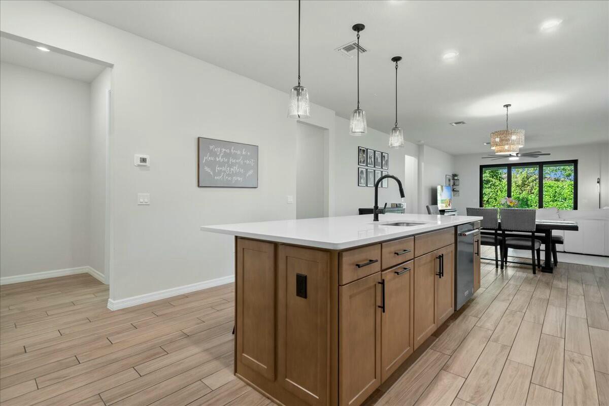 A kitchen island with wood cabinets and white countertops sits in an open-concept living space — 4801 Chantilly Road, Lake Worth FL 33467, LAKE WORTH, FL