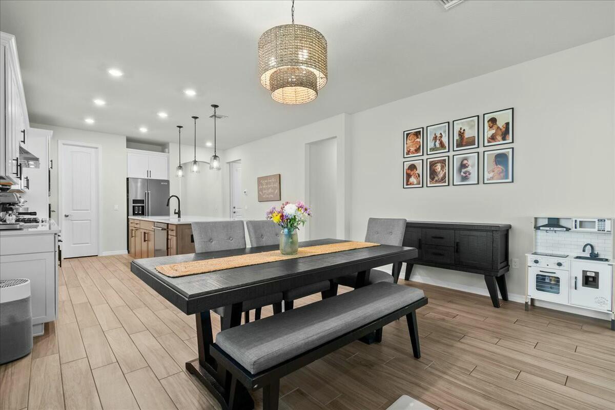 A dining area with a dark wood table, gray bench, and a nearby toy kitchen — 4801 Chantilly Road, Lake Worth FL 33467, LAKE WORTH, FL