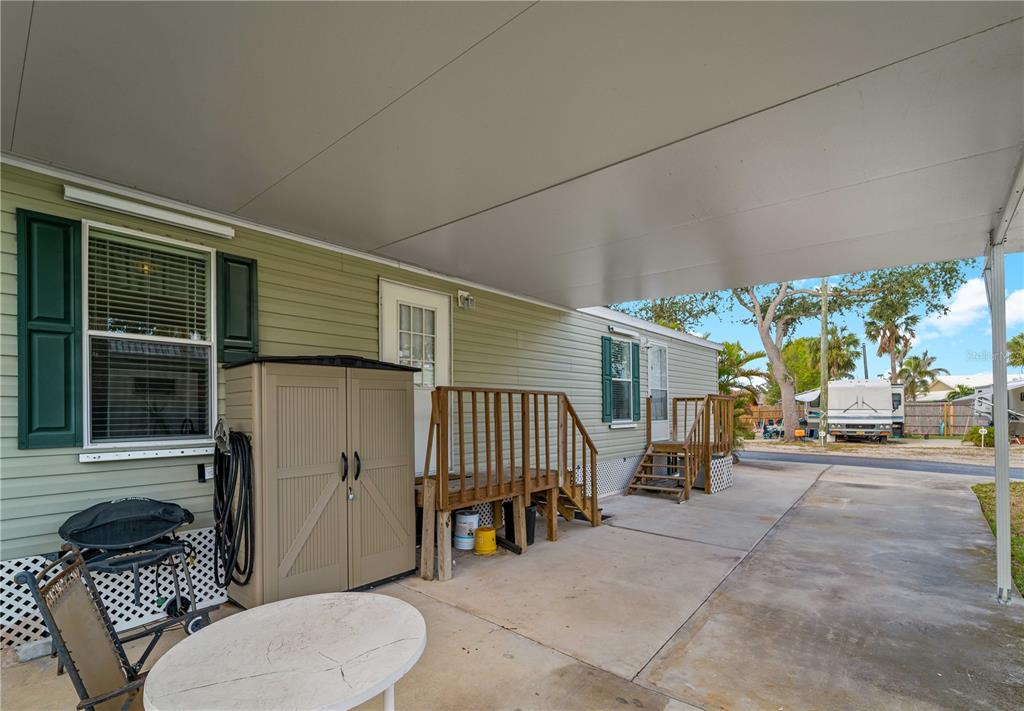 A covered concrete patio area features two sets of wooden stairs leading to house doors — 1800 ENGLEWOOD ROAD UNIT 24, ENGLEWOOD, FL