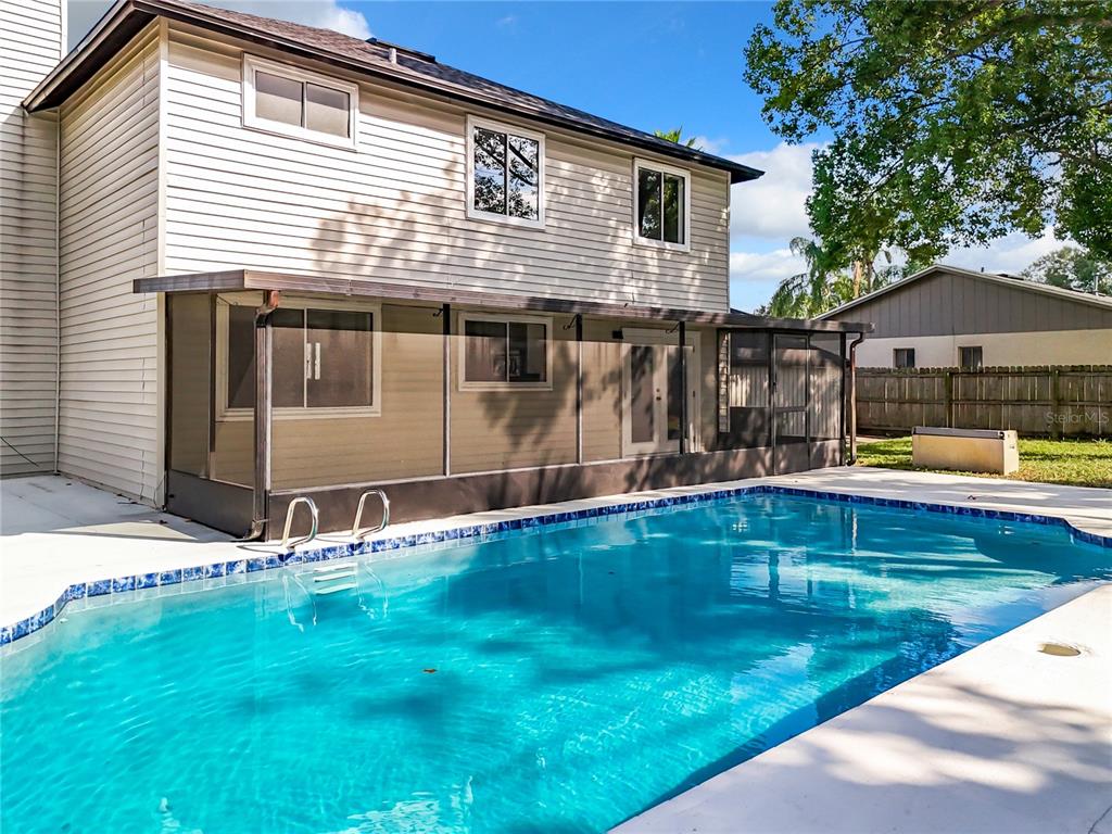 A two-story house with light siding features a screened-in patio overlooking a rectangular swimming pool — 1040 WAVERLY DRIVE, LONGWOOD, FL