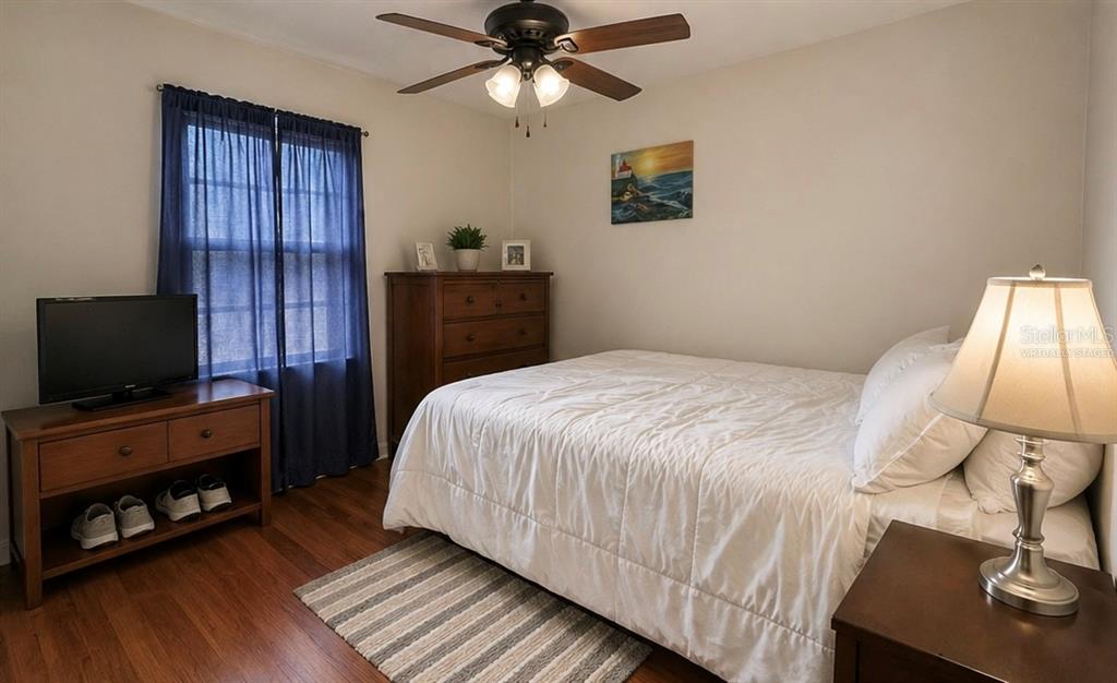 A kitchen features white cabinets, stainless steel appliances, a small round table, and wood flooring — 8604 N BRANCH AVENUE, TAMPA, FL