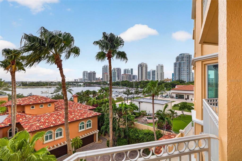 A balcony view overlooking a marina, palm trees, and a city skyline under a blue sky — 555 5TH AVENUE NE UNIT 521, ST PETERSBURG, FL