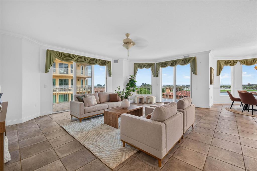 A living room with tile floors, neutral furniture, and large windows overlooking a balcony — 555 5TH AVENUE NE UNIT 521, ST PETERSBURG, FL