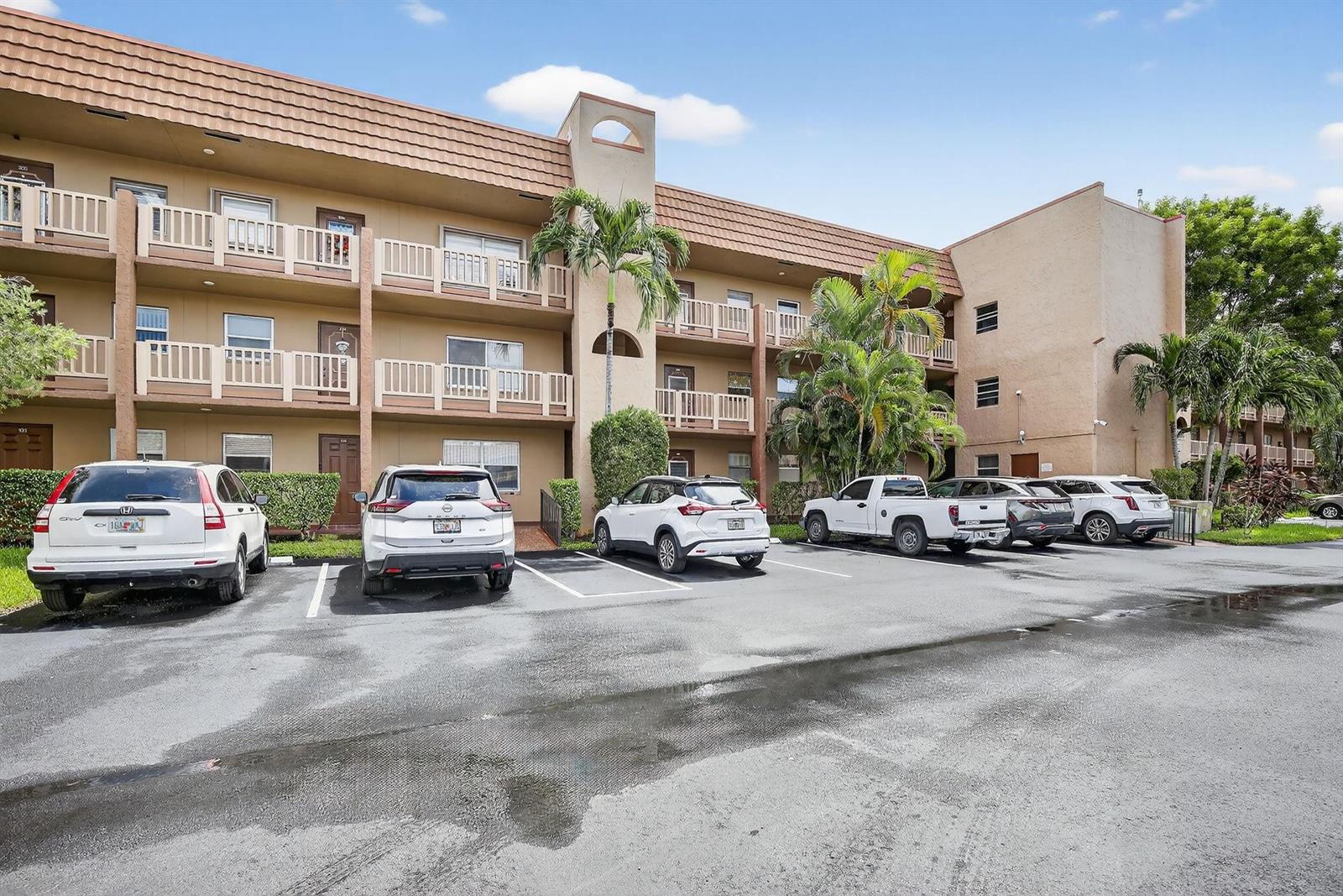 A three-story apartment building with tan stucco walls and a parking lot in front — 9660 Sunrise Lakes Boulevard # 306, Sunrise FL 33322, SUNRISE, FL