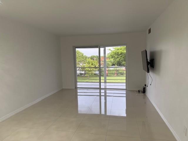 An empty room with white walls, light tile flooring, and a sliding glass door to a balcony — 9660 Sunrise Lakes Boulevard # 306, Sunrise FL 33322, SUNRISE, FL