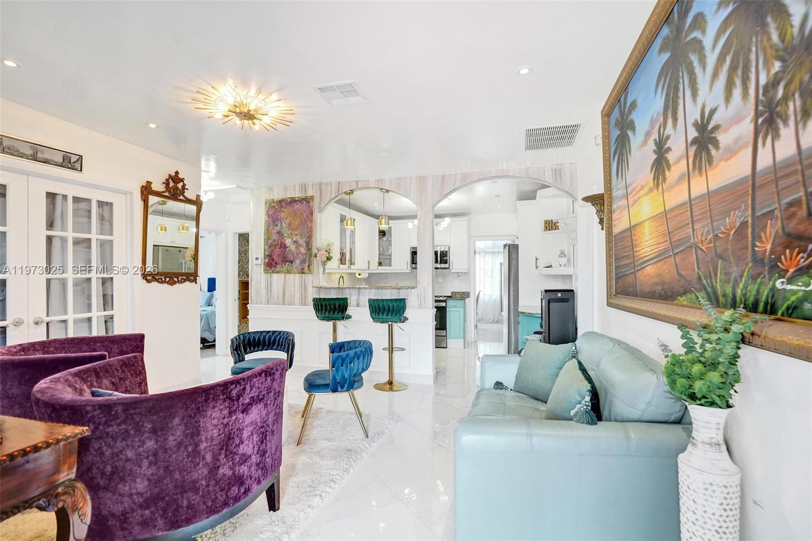 A living room and kitchen area feature purple and blue seating, white tile floors, and arches — 609 SW 2nd Ave, Hallandale Beach FL 33009, HALLANDALE BEACH, FL