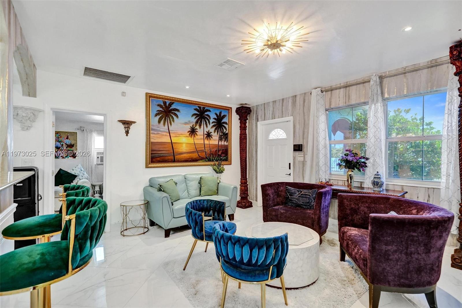 A living room features white marble floors, a sunset painting, and a mix of colorful furniture — 609 SW 2nd Ave, Hallandale Beach FL 33009, HALLANDALE BEACH, FL