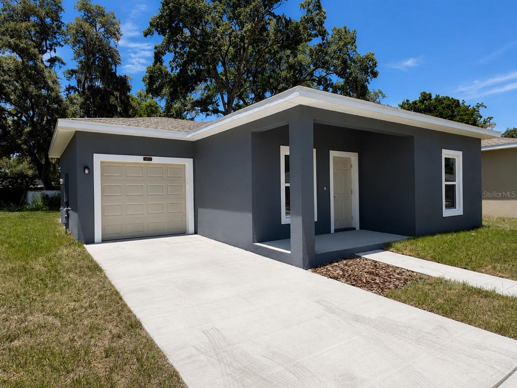 A single-story house with gray stucco siding, a tan garage door, and a covered porch — 5012 FINDERS CT, TAMPA, FL