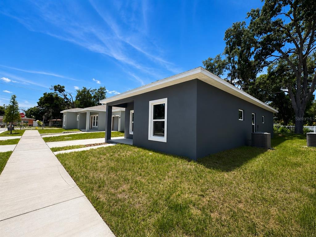 A gray, single-story house with a white-trimmed window sits next to a sidewalk — 5012 FINDERS CT, TAMPA, FL