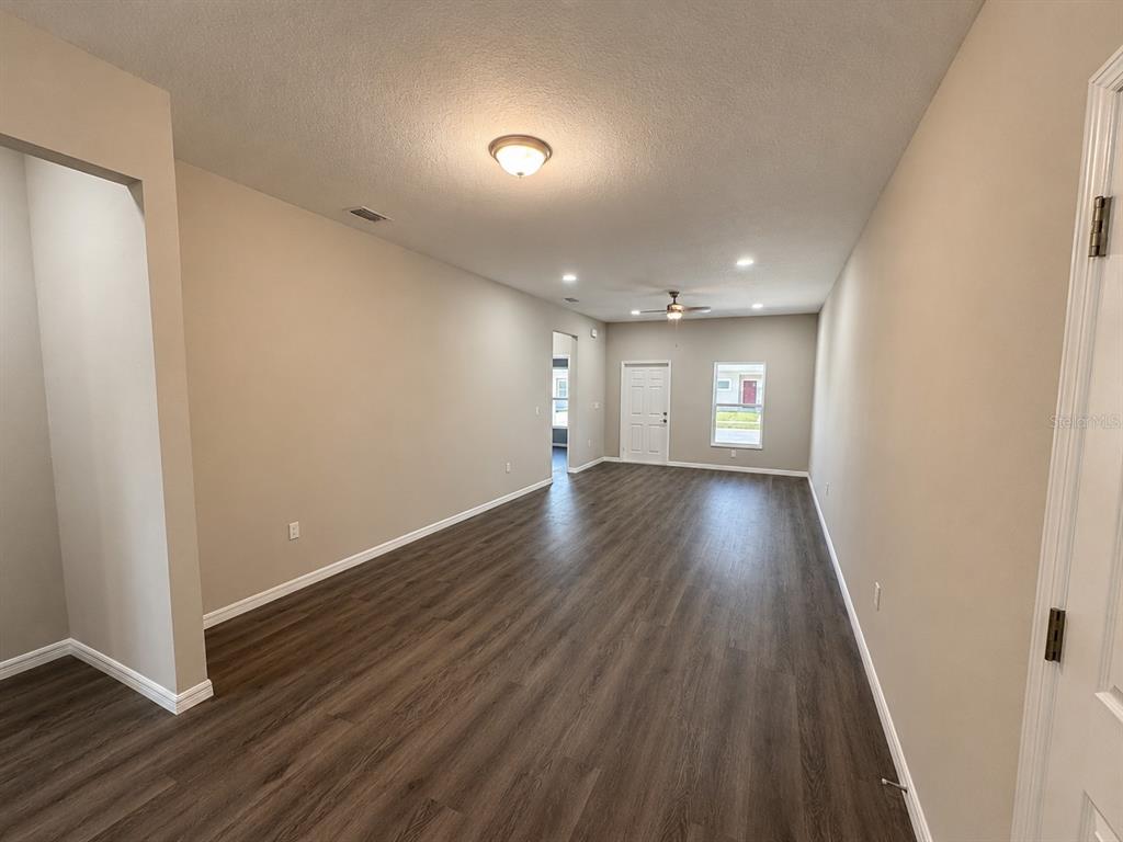 An empty living area features wood-look flooring, beige walls, a ceiling fan, and recessed lighting — 5012 FINDERS CT, TAMPA, FL