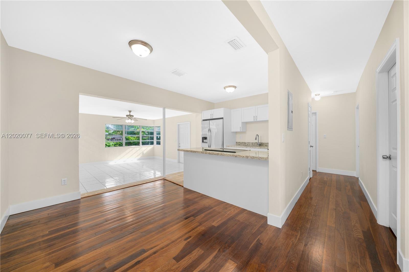A kitchen with granite countertops overlooks a dining area and a sunroom with tile floors — 3271 NW 18th Ter, Miami FL 33125, MIAMI, FL