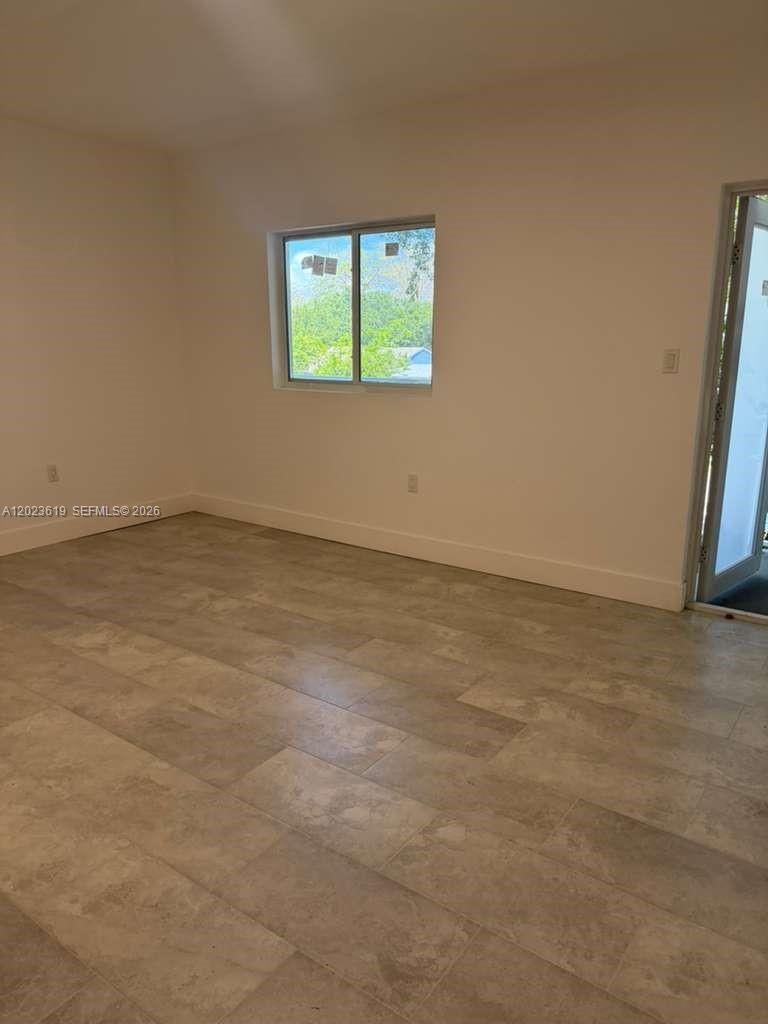 An empty room features light-colored tile flooring, white walls, and a single window — 147 Nw 59th St # 304, Miami FL 33127, MIAMI, FL