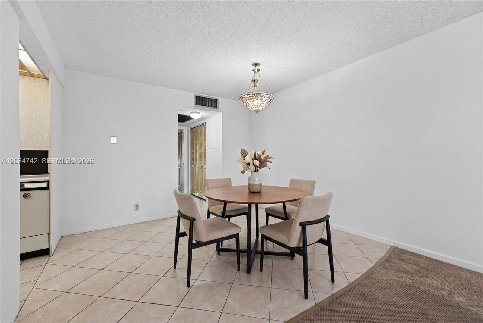 A dining area features a round wooden table, four chairs, and a decorative pendant light — 2401 Antigua Cir # E3, Coconut Creek FL 33066, COCONUT CREEK, FL