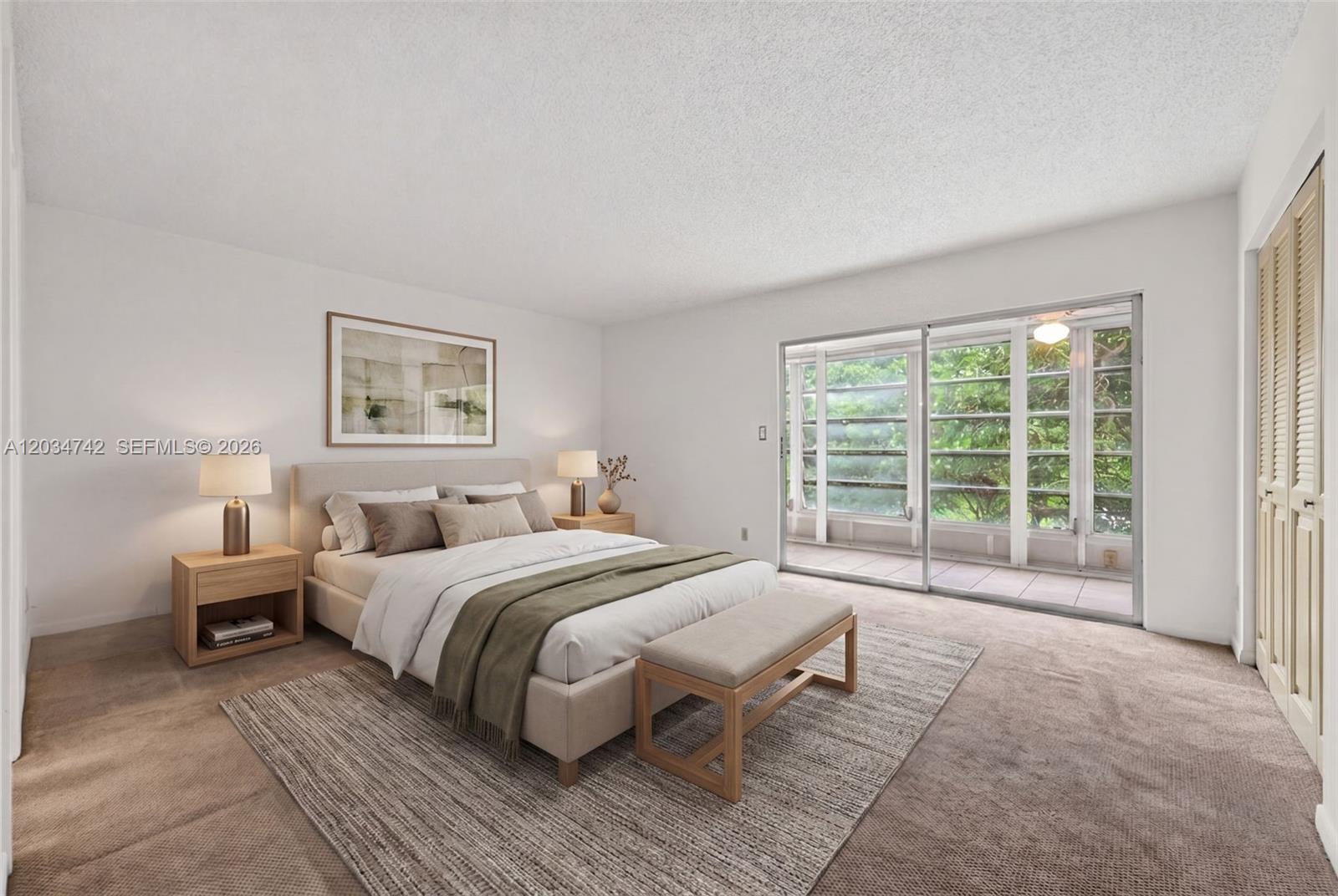 A bedroom features a bed with a green throw, two nightstands, and sliding glass doors — 2401 Antigua Cir # E3, Coconut Creek FL 33066, COCONUT CREEK, FL