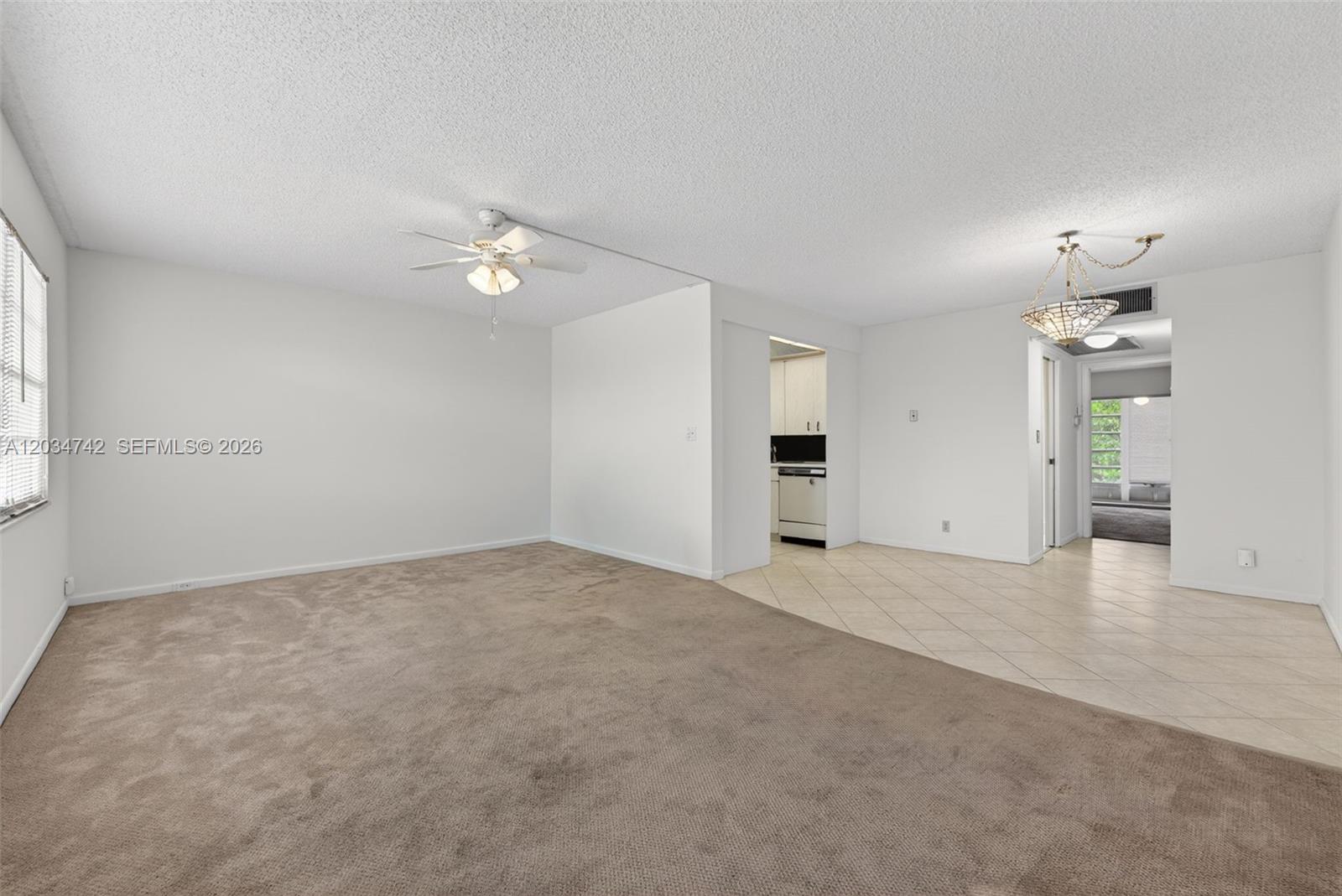 A living room features beige carpeting, a ceiling fan, and an adjacent tiled dining area — 2401 Antigua Cir # E3, Coconut Creek FL 33066, COCONUT CREEK, FL
