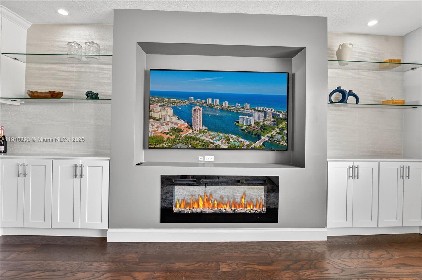 A living room features a wall-mounted television above an electric fireplace with built-in shelving — 5660 Golfway Dr # 0, Boca Raton FL 33433, BOCA RATON, FL