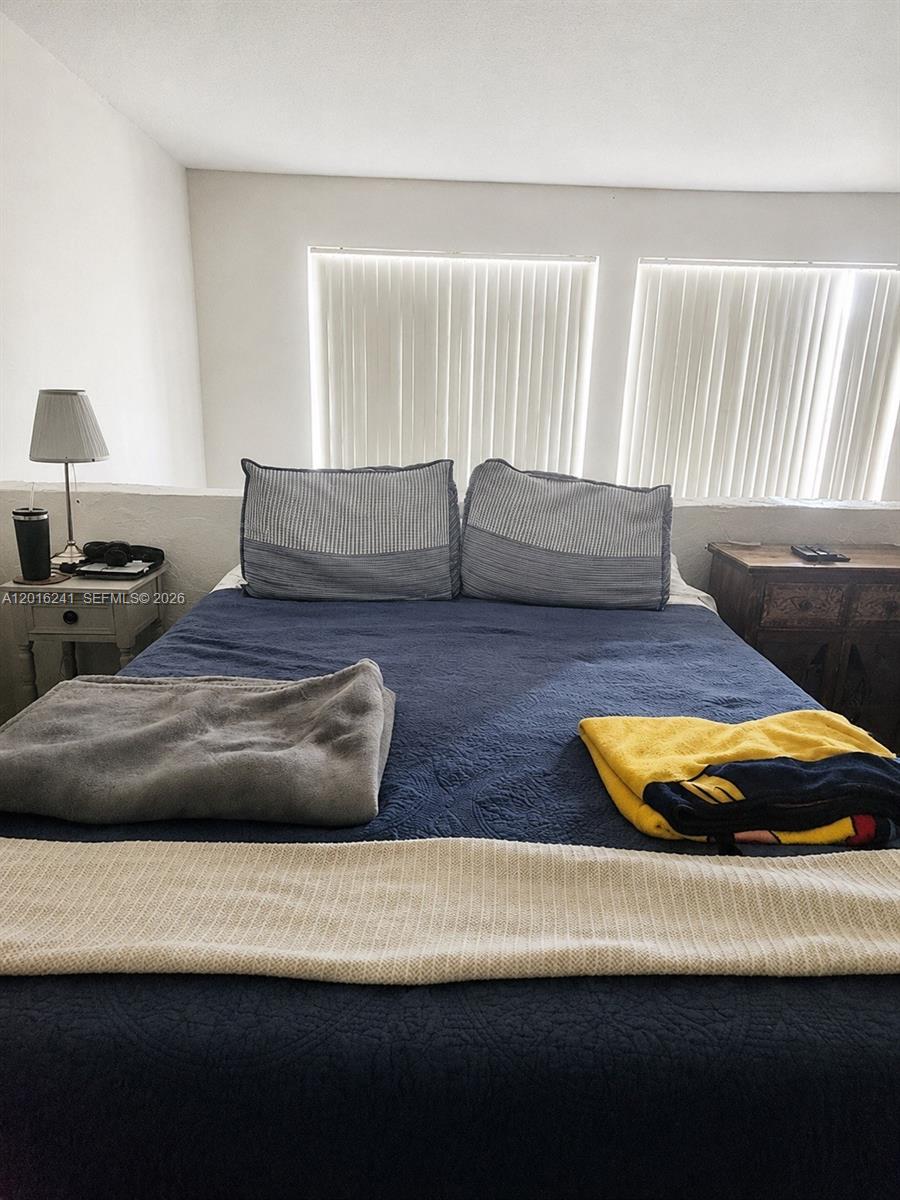 A bedroom features a bed with a blue quilt, two pillows, and two nightstands — 18051 NW 68th Ave # K201, Hialeah FL 33015, HIALEAH, FL