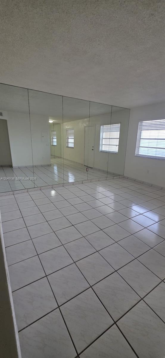 A room with white tiled floors and a wall covered in large floor-to-ceiling mirrors — CORAL GABLES, FL