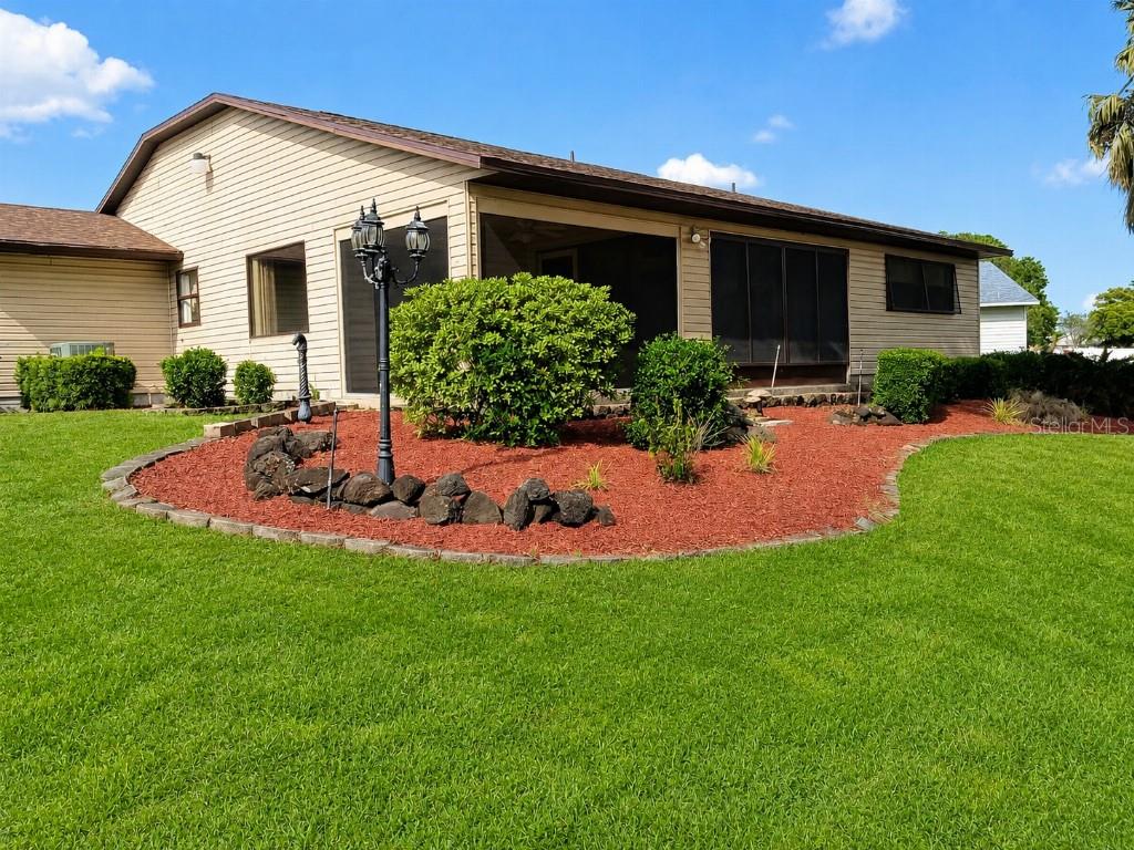 A tan house with a screened-in porch and a landscaped garden bed with red mulch — 3104 SAND TRAP COURT, LAKELAND, FL
