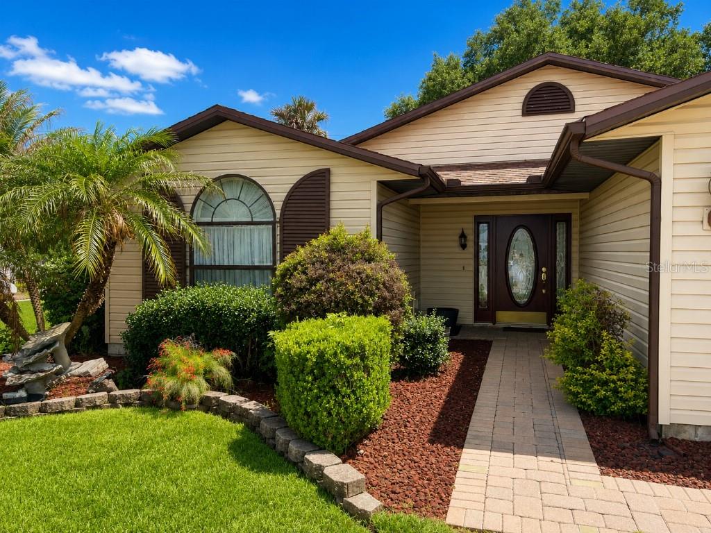 A single-story house with tan siding, a brick walkway, and a landscaped front yard — 3104 SAND TRAP COURT, LAKELAND, FL