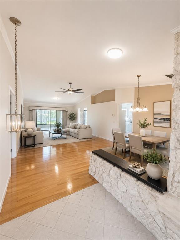 An open-concept living and dining area features hardwood floors, a stone half-wall, and vaulted ceilings — 3104 SAND TRAP COURT, LAKELAND, FL