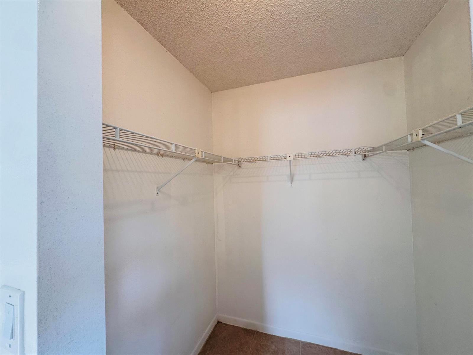 An empty walk-in closet features white walls, a textured ceiling, and wire shelving — 20681 NE 4th Place # 105, Miami FL 33179, MIAMI, FL