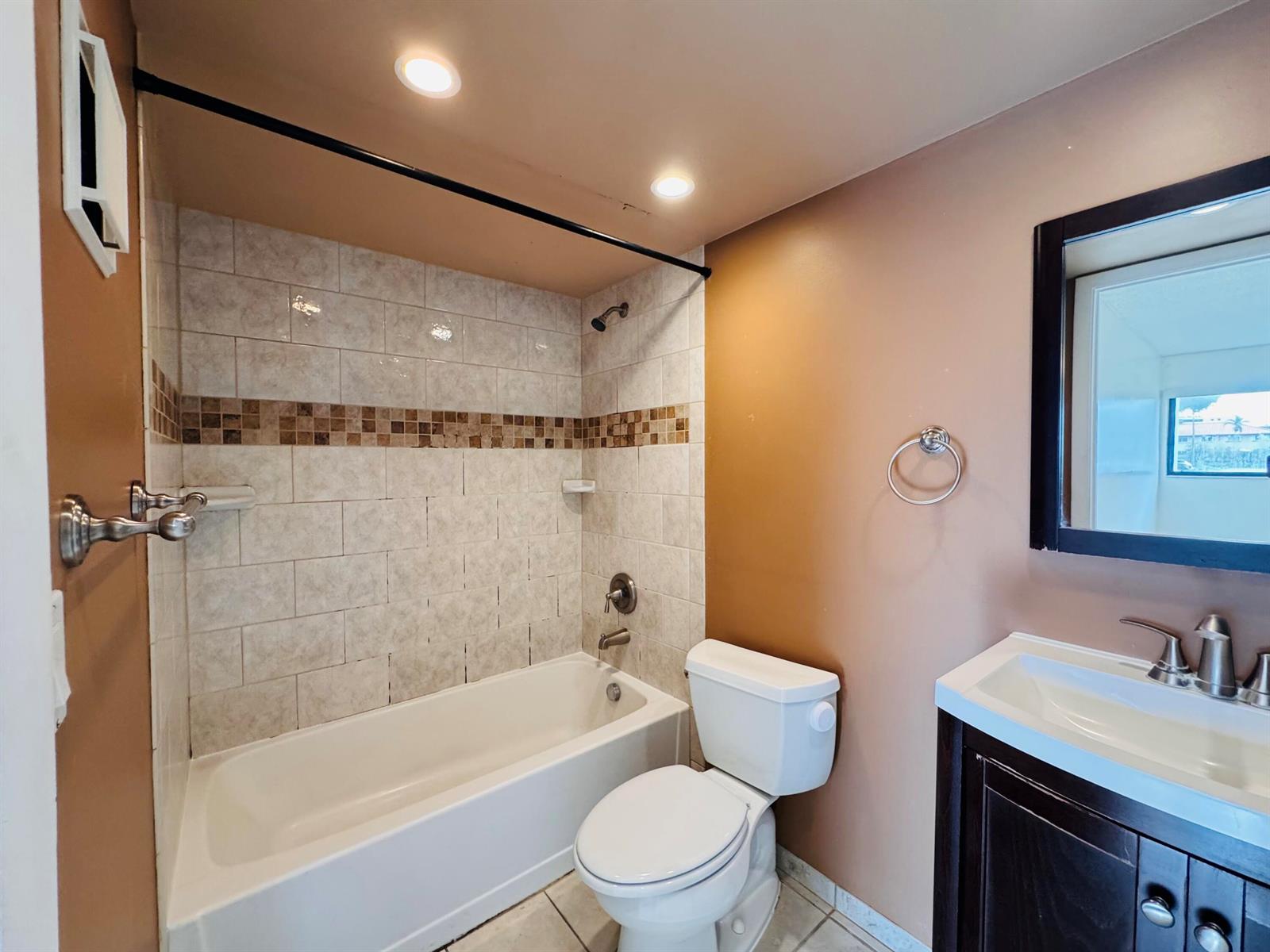 A bathroom features a tiled shower-tub combination, a white toilet, and a dark wood vanity — 20681 NE 4th Place # 105, Miami FL 33179, MIAMI, FL