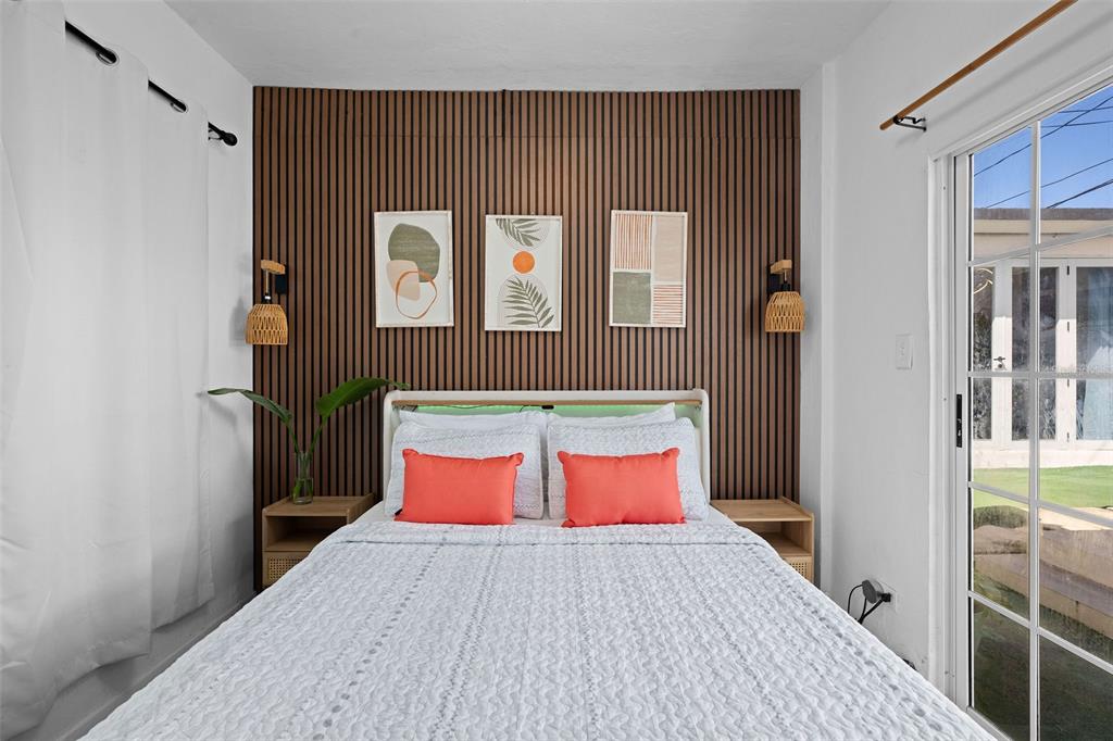 A bedroom features a wood-slat accent wall, a bed with coral pillows, and sliding glass doors — 4 MAR DEL JAPON, CAROLINA, PR