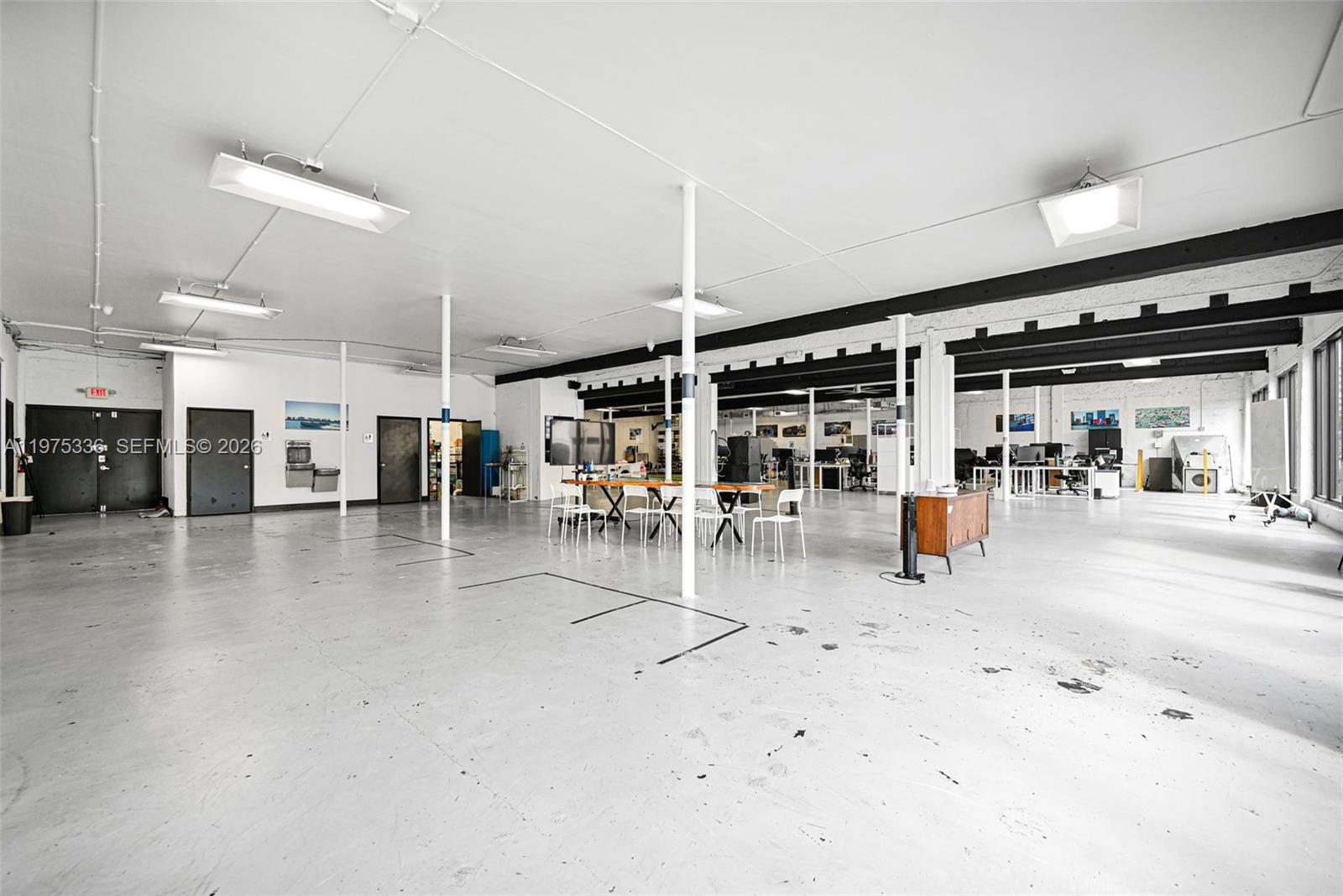 An open-plan office space features white walls, exposed ceiling beams, and a light gray floor — 101 NE 79th St, Miami FL 33138, MIAMI, FL