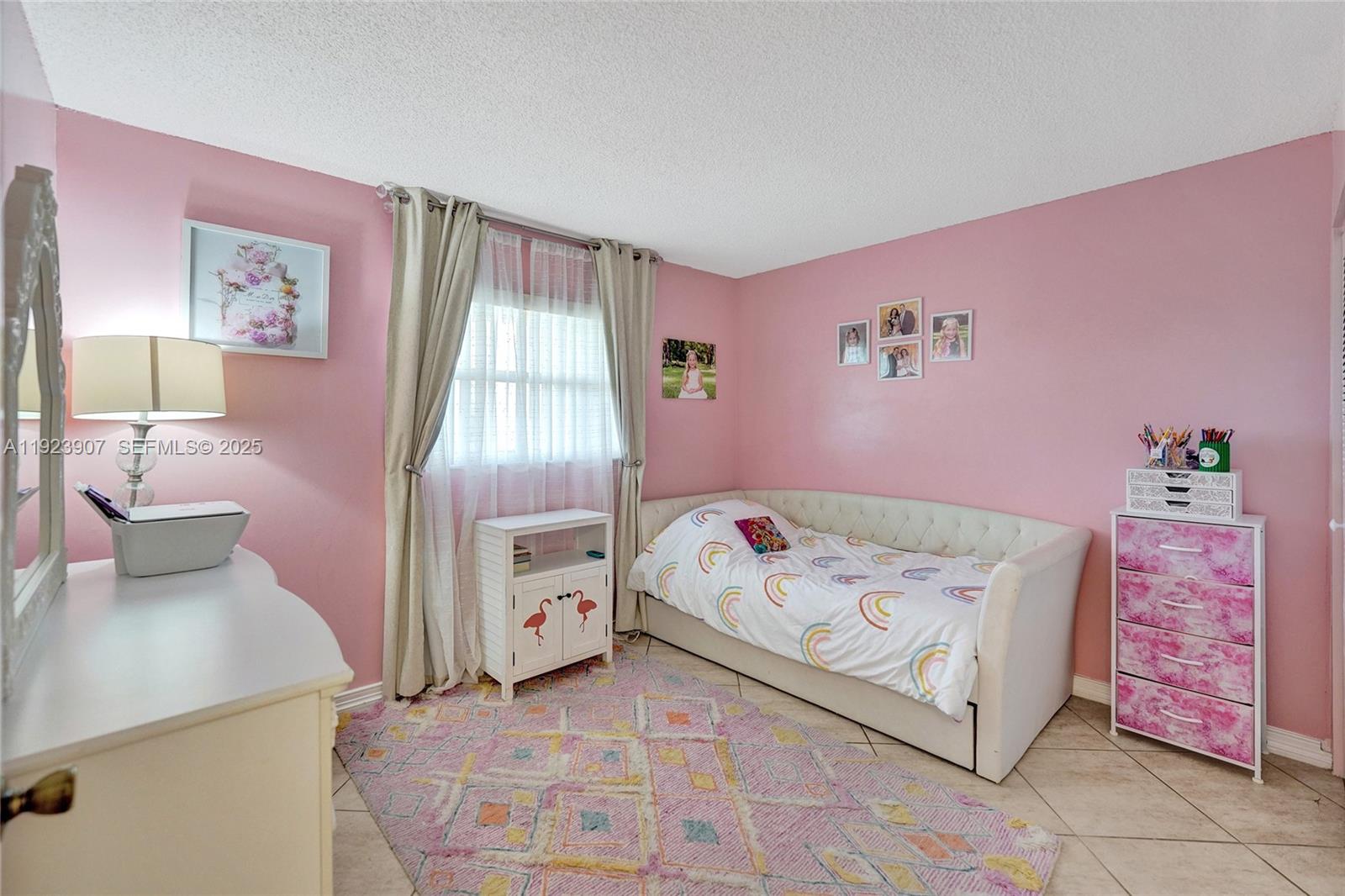 A pink-walled bedroom features a daybed, a small cabinet, a dresser, and a patterned rug — 4111 Stirling Rd # 502, Dania Beach FL 33314, DANIA BEACH, FL