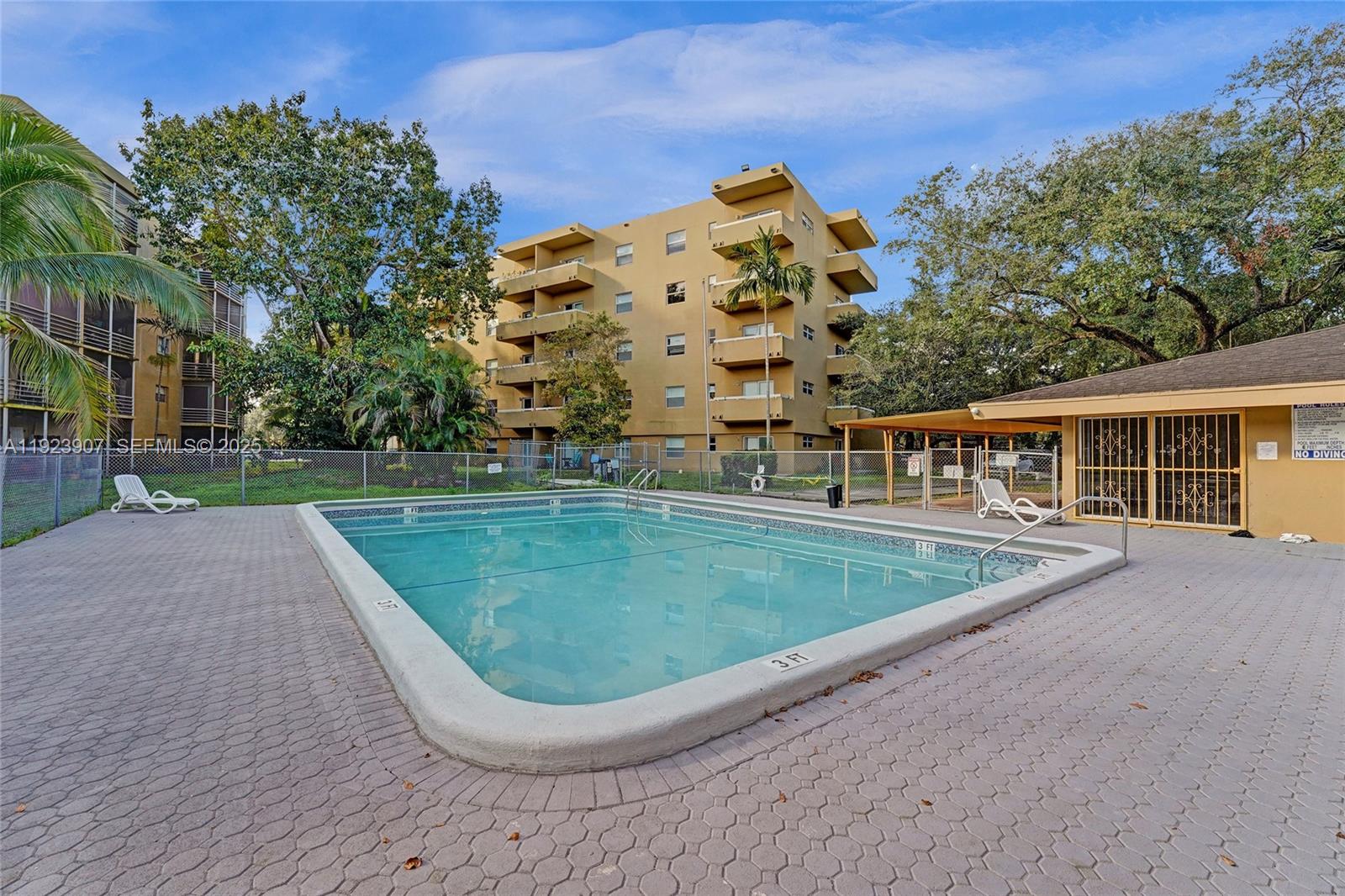 A rectangular swimming pool sits on a paved deck in front of a multi-story building — 4111 Stirling Rd # 502, Dania Beach FL 33314, DANIA BEACH, FL