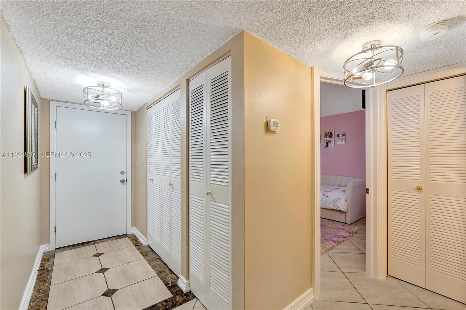A hallway features tiled floors, louvered closet doors, and a doorway leading to a bedroom — 4111 Stirling Rd # 502, Dania Beach FL 33314, DANIA BEACH, FL