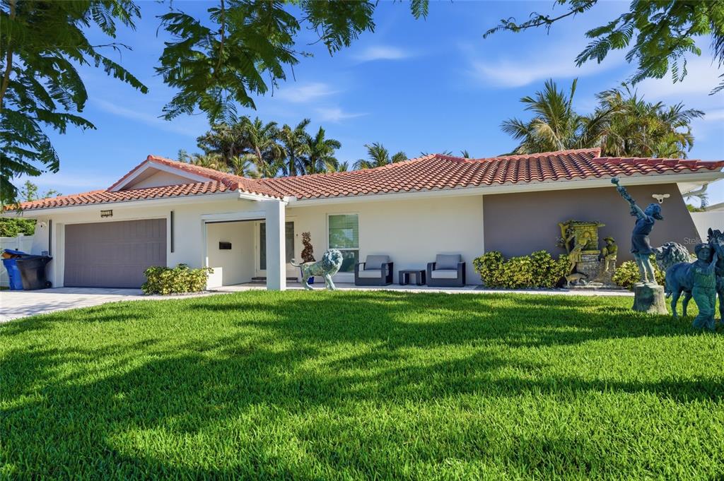 A single-story house with a tile roof, garage, and lawn statues under a blue sky — 3874 48TH AVENUE S, ST PETERSBURG, FL
