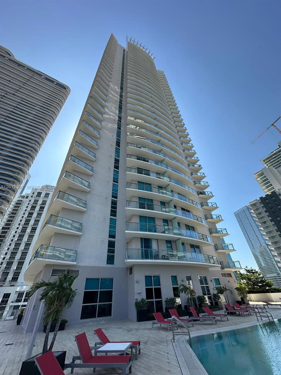 A low-angle view of a tall residential skyscraper with balconies overlooking a swimming pool — 1100 S Miami Ave # 2608, Miami FL 33130, MIAMI, FL