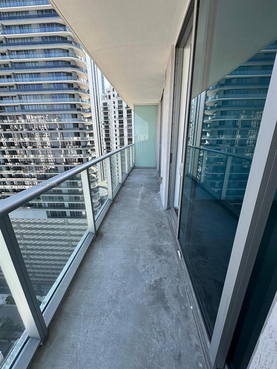 A narrow balcony with a glass railing overlooks high-rise buildings in an urban setting — 1100 S Miami Ave # 2608, Miami FL 33130, MIAMI, FL